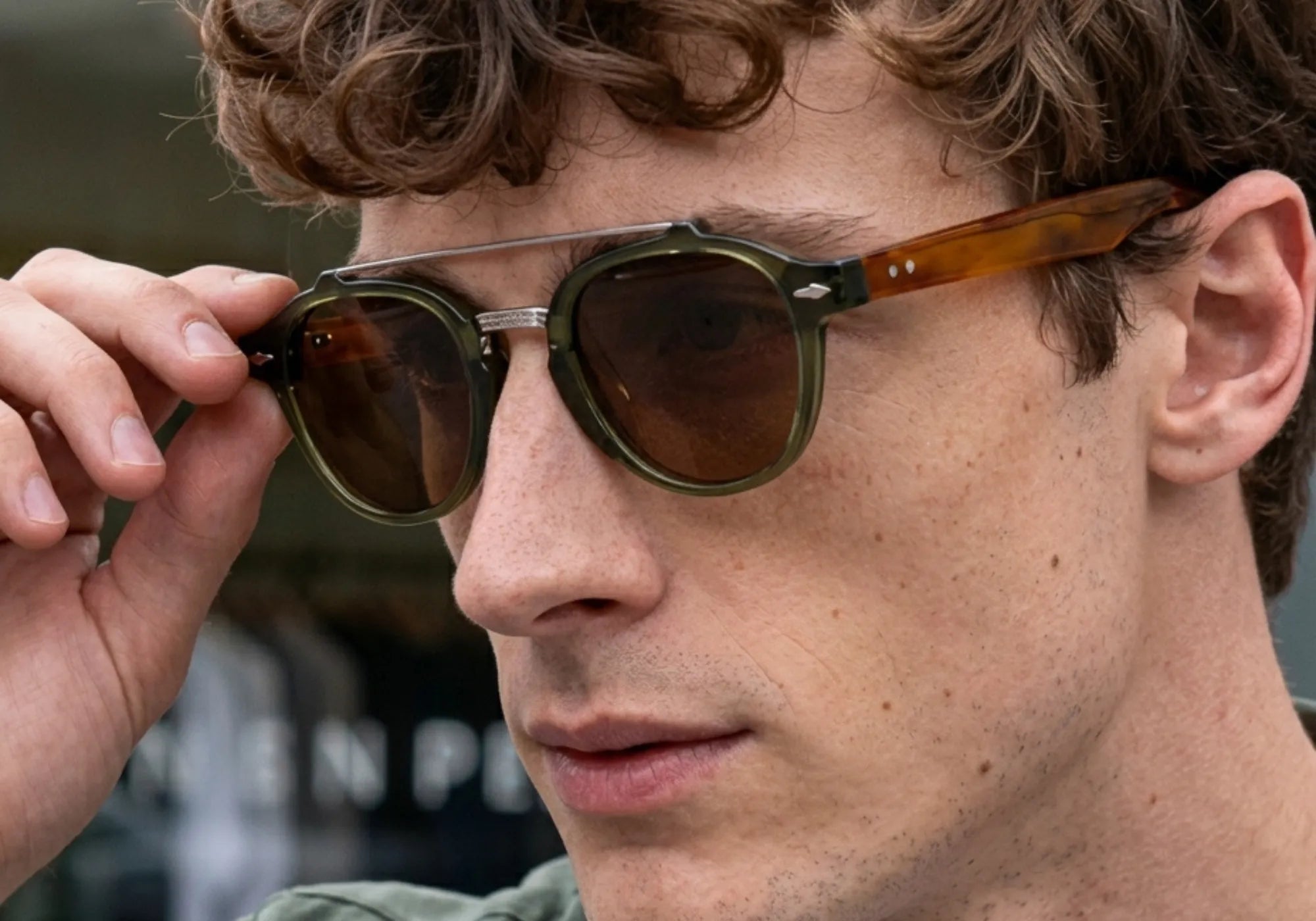 Homem Usando o Óculos Cannes Polarizado Verde com Lentes Marrons na Cidade