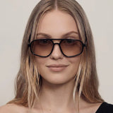 Mulher Usando o Óculos Essenza UV400 na Cor Preta com Lentes Marrons